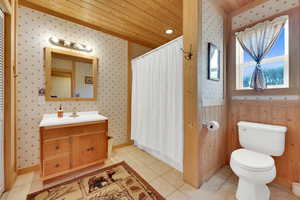 Bathroom with wallpapered walls, vanity, a shower with curtain, and light tile patterned floors
