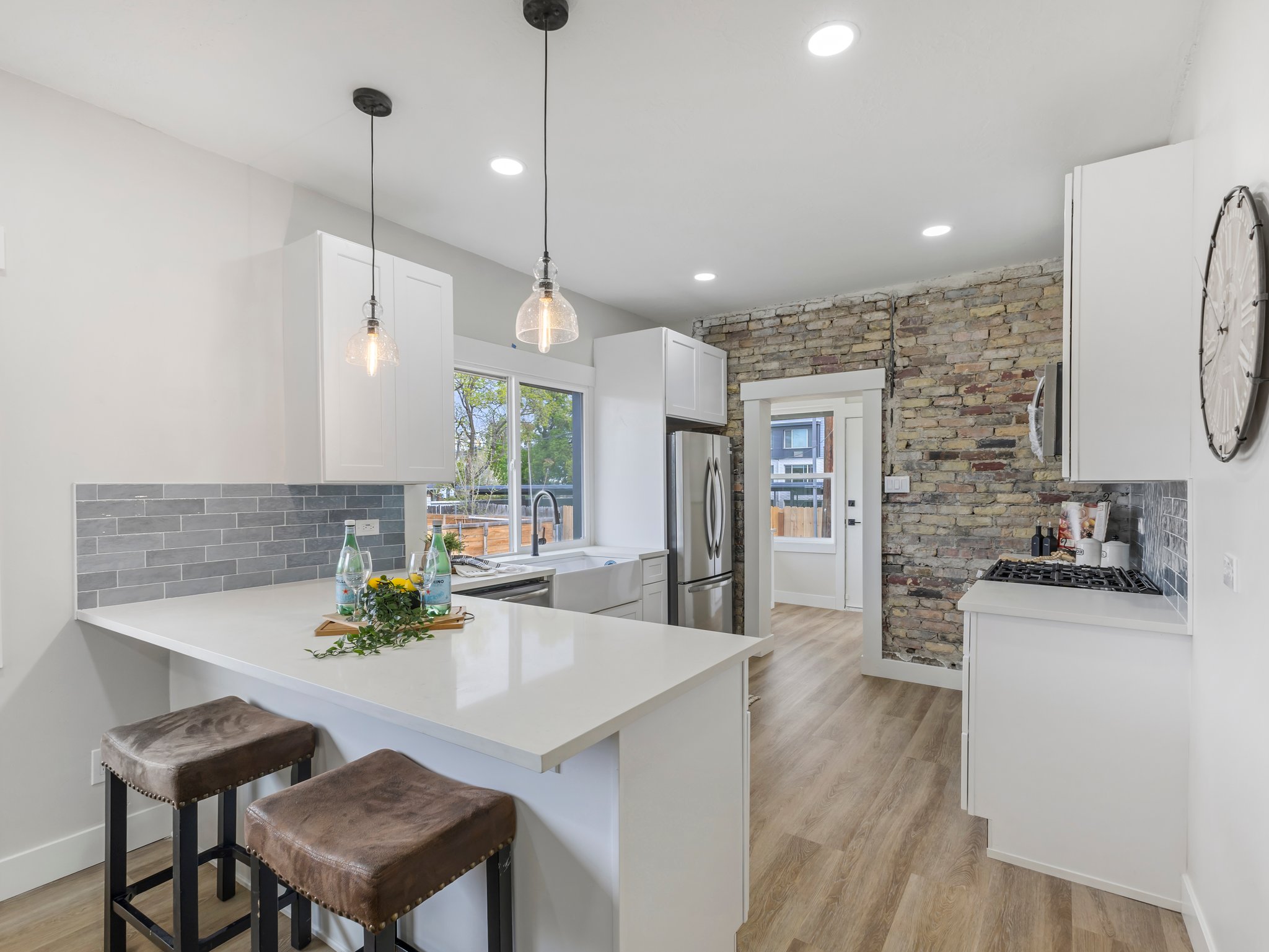 Kitchen featuring a breakfast bar, decorative backsplash, light wood finished floors, white cabinetry, and a peninsula