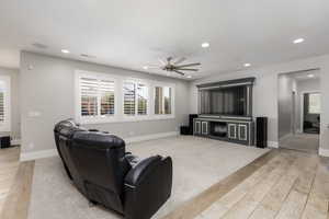 Living area featuring light wood-style flooring, ceiling fan, and recessed lighting