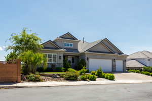 Craftsman-style house featuring stone siding, an attached garage, stucco siding, and driveway