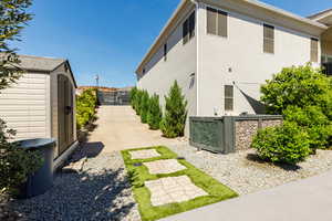 View of side of home featuring a shed, stucco siding, and a gate