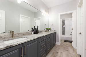 Bathroom featuring double vanity, shower / bathtub combination with curtain, and light wood finished floors