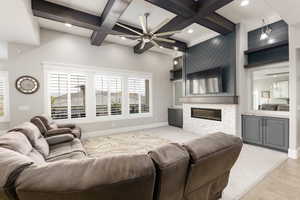 Living room with a ceiling fan, coffered ceiling, a stone fireplace, and recessed lighting