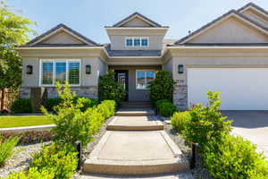 View of front of property featuring stone siding, stucco siding, and a garage