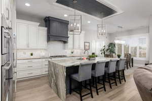 Kitchen with light stone countertops, hanging lights, a breakfast bar area, and light wood-style floors