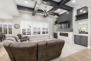 Living area featuring a ceiling fan, coffered ceiling, a fireplace, light wood-style floors, and recessed lighting