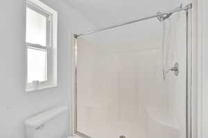 Full bath featuring a shower stall and toilet