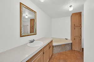 Bathroom with a bath, vanity, and a textured ceiling