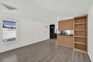 Kitchen featuring dark countertops, open shelves, wood finish cabinetry, dark wood-style flooring, and open floor plan