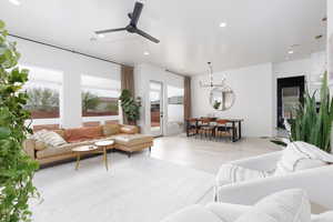 Living room with a ceiling fan, light wood-style floors, and suspended lighting
