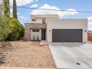 Contemporary home with an attached garage, concrete driveway, stucco siding, and stone siding