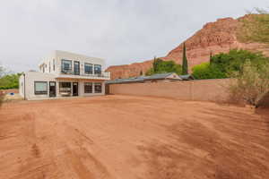 Back of house with stucco siding, a mountain view, a fenced backyard, a balcony, and a patio area