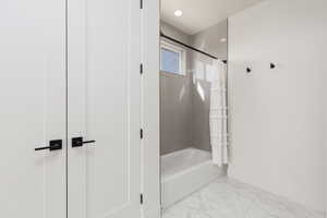 Full bathroom featuring shower / tub combo, light marble finish floors, and recessed lighting