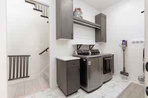 Laundry area with cabinet space, light marble finish flooring, and washer and clothes dryer