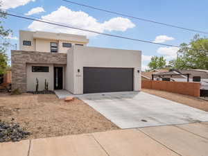 Modern home with concrete driveway, stucco siding, a garage, and stone siding