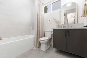 Full bathroom with vanity, light tile patterned flooring, and shower / bath combo with shower curtain
