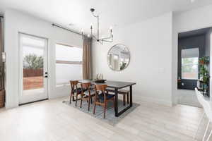 Dining space with a chandelier, light wood-style floors, and plenty of natural light