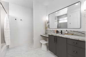 Bathroom with vanity, light marble finish floors, and shower / bathtub combination with curtain