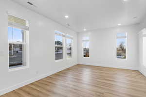 Spare room featuring light wood-style flooring, plenty of natural light, and recessed lighting