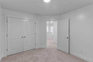 Unfurnished bedroom featuring light colored carpet and a closet