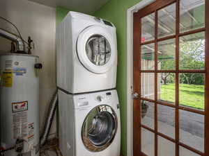 Laundry room featuring gas water heater and stacked washer / dryer