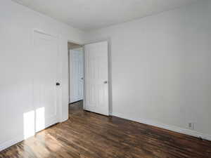 Empty room featuring dark wood finished floors and a textured ceiling