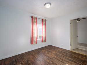 Unfurnished room featuring dark wood-style floors, a textured ceiling, and a ceiling fan