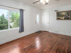Entrance foyer with dark wood-style flooring, a textured wall, and ceiling fan