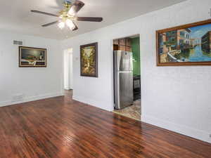 Unfurnished room featuring a textured wall, hardwood / wood-style flooring, and a ceiling fan