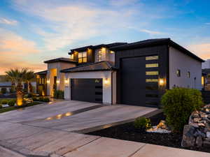 Modern home with concrete driveway, an attached garage, brick siding, and board and batten siding