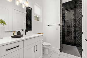 Bathroom with vanity, light tile patterned flooring, and tiled shower