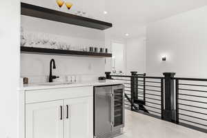 Bar area featuring open shelves, beverage cooler, white cabinets, and recessed lighting