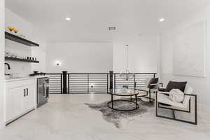 Sitting room with beverage cooler, a chandelier, and light marble finish floors