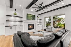 Living room featuring a glass covered fireplace, light wood-style flooring, ceiling fan, recessed lighting, and wooden ceiling