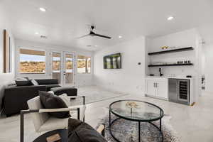 Living area featuring french doors, beverage cooler, bar with sink, ceiling fan, and recessed lighting