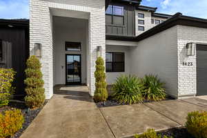 Property entrance featuring brick siding, an attached garage, and stucco siding