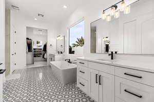 Bathroom with a soaking tub, two vanities, recessed lighting, and a spacious closet