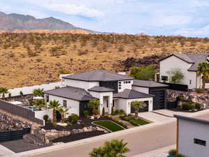 View of front of house featuring a mountain view, concrete driveway, stucco siding, a garage, and view of desert landscape
