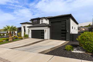 View of front facade featuring driveway, an attached garage, brick siding, and a standing seam roof