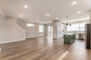 Dual tone kitchen featuring stainless steel appliances, open floor plan, plenty of natural light, light wood-type flooring, and dual tone cabinetry