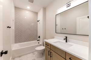 Bathroom with vanity, light marble finish flooring, tub / shower combination, and recessed lighting