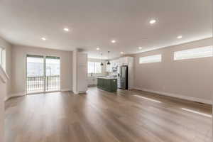 Dual tone kitchen featuring open floor plan, two tone cabinets, stainless steel appliances, light wood-style flooring, and light countertops