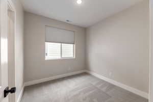 Empty room with light colored carpet and baseboards