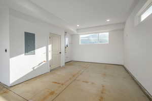 Garage featuring electric panel, recessed lighting, and tankless water heater