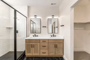 Full bathroom featuring double vanity, a shower stall, and a spacious closet