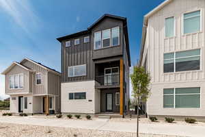 Modern home featuring board and batten siding, a balcony, and brick siding