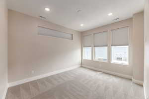 Empty room with light carpet and recessed lighting