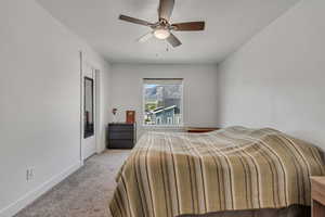 Carpeted bedroom featuring baseboards and ceiling fan