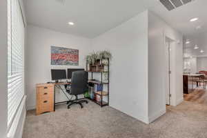 Office with light carpet and recessed lighting