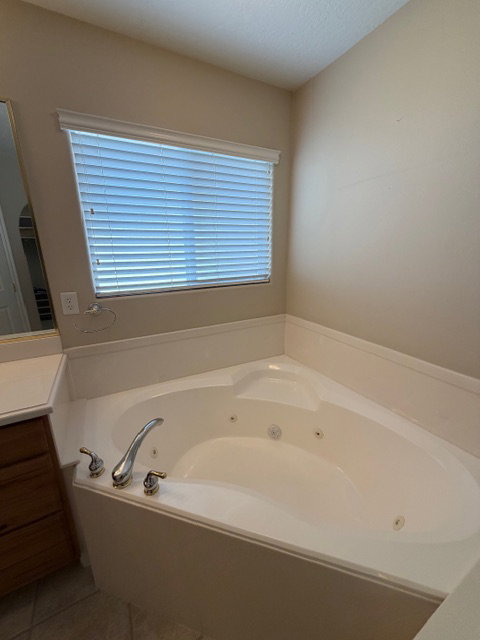 Bathroom featuring vanity, a jetted tub, and light tile patterned flooring